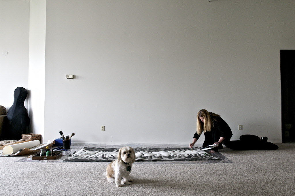 Meghan Caughey works on a sumi-e piece (Japanese for black ink painting) in her studio apartment, with her dog, Ananda. (Benjamin Brink / The Oregonian)